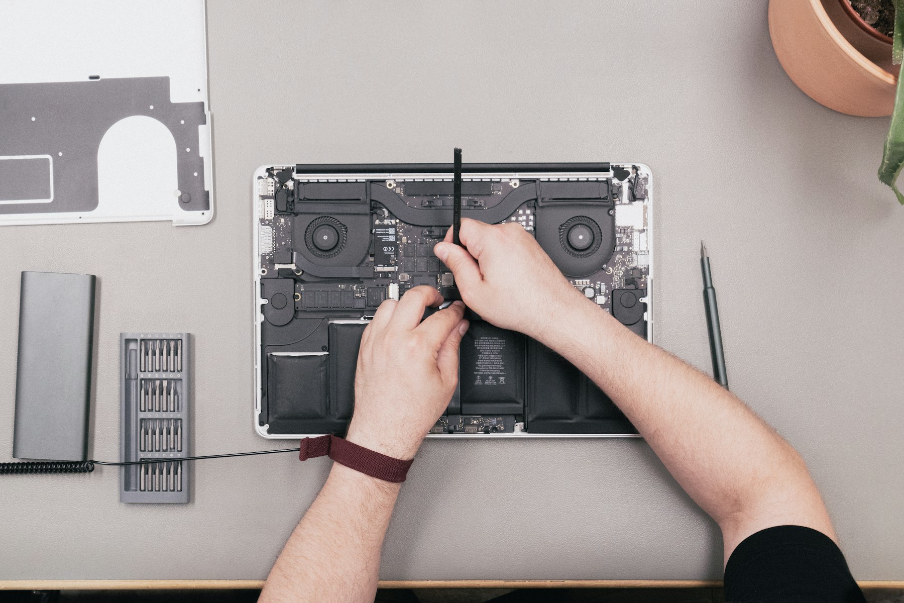 A technician lifting a component out of an opened laptop at the Computer Village bench
