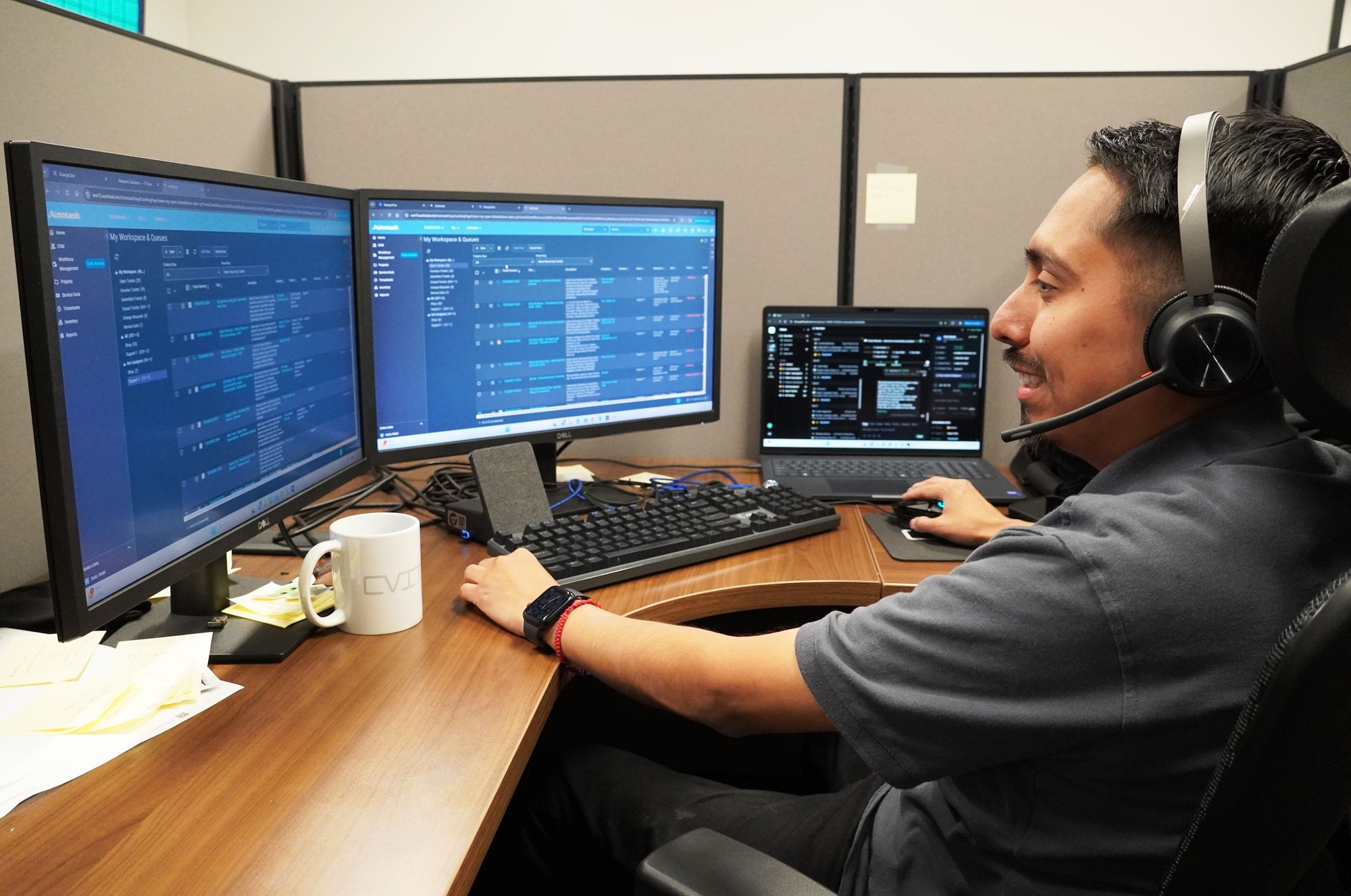 A Computer Village technician at a desk in a headset with the ticket queue open